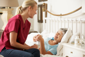 Health Visitor Talking To Senior Woman Patient In Bed